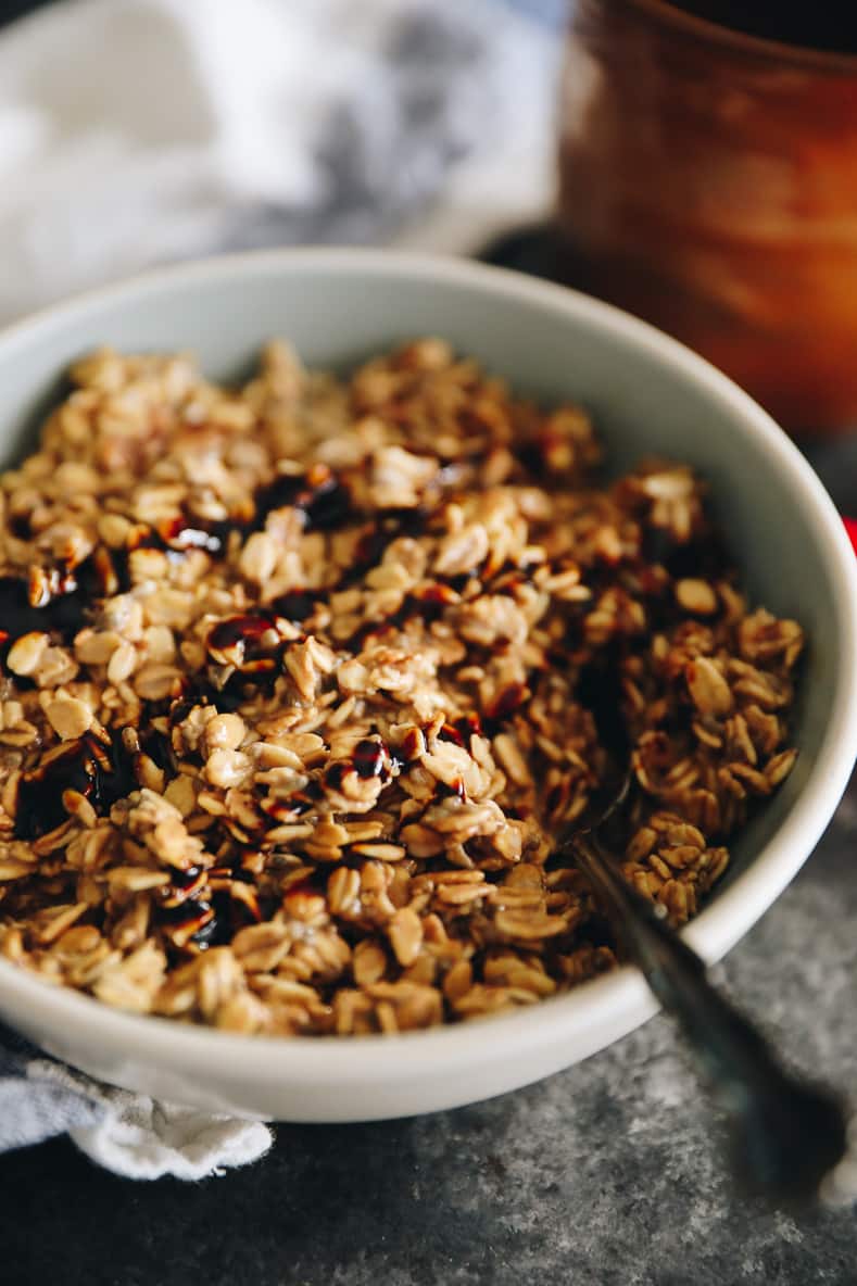 Angled shot of gingerbread overnight oats in a white bowl with a spoon sticking out.