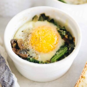 One ramekin with vegetables, baked eggs and spices inside.