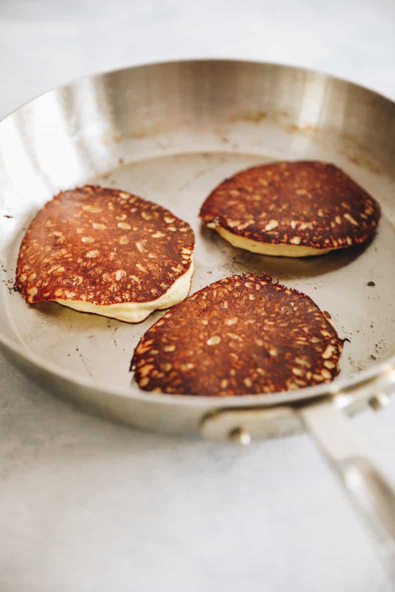 3 protein powder pancakes in silver frying pan.