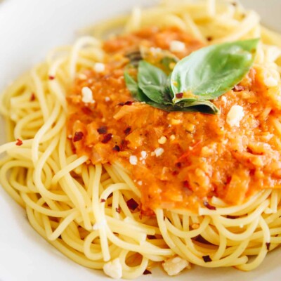Plate of noodles topped with arrabbiata sauce and fresh basil.