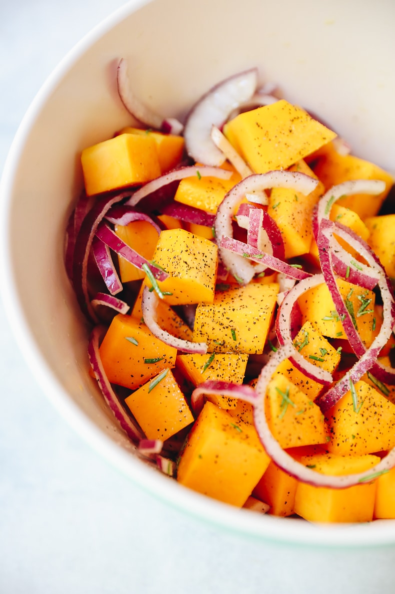 raw butternut squash and rosemary in a bowl