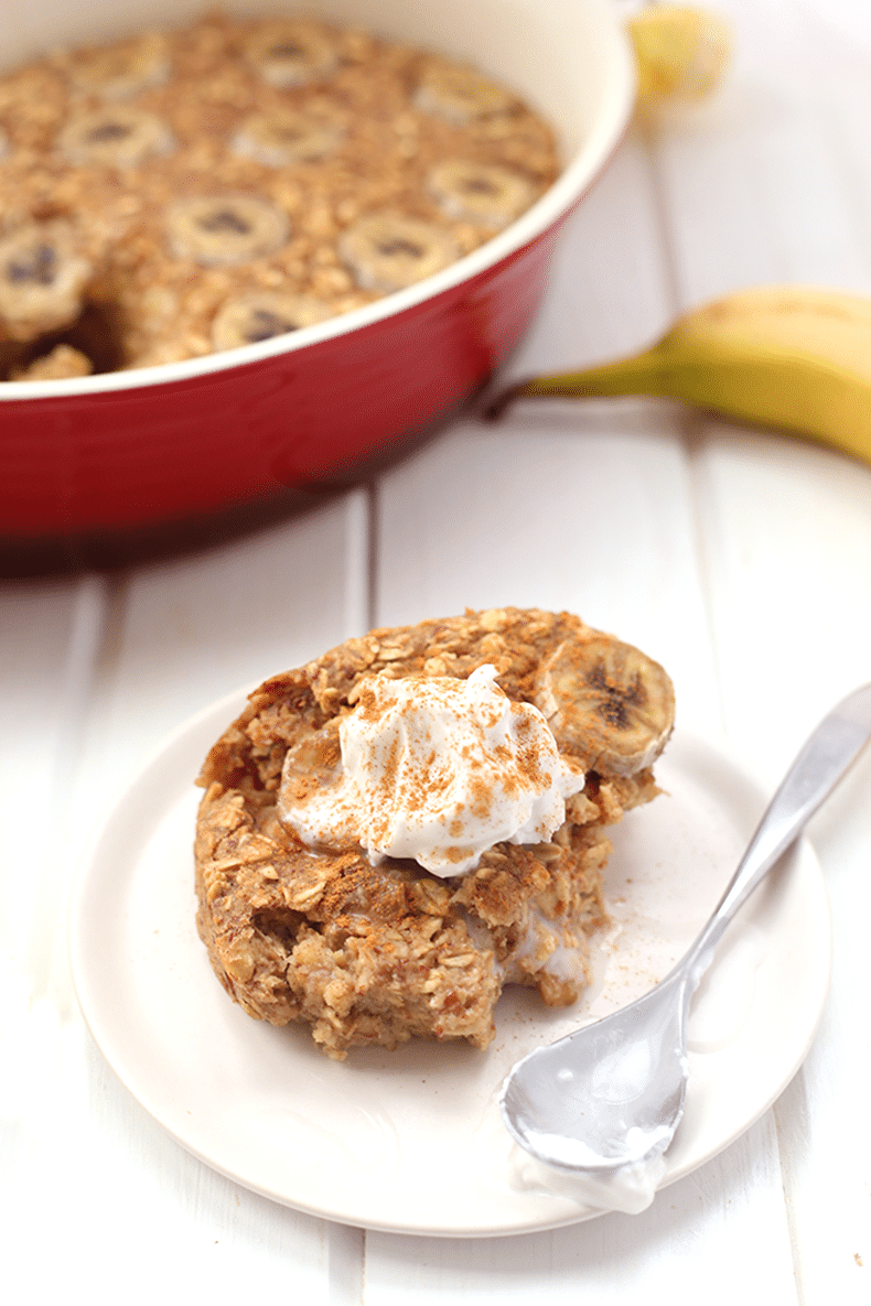 banana baked oatmeal on a plate topped with coconut cream and cinnamon