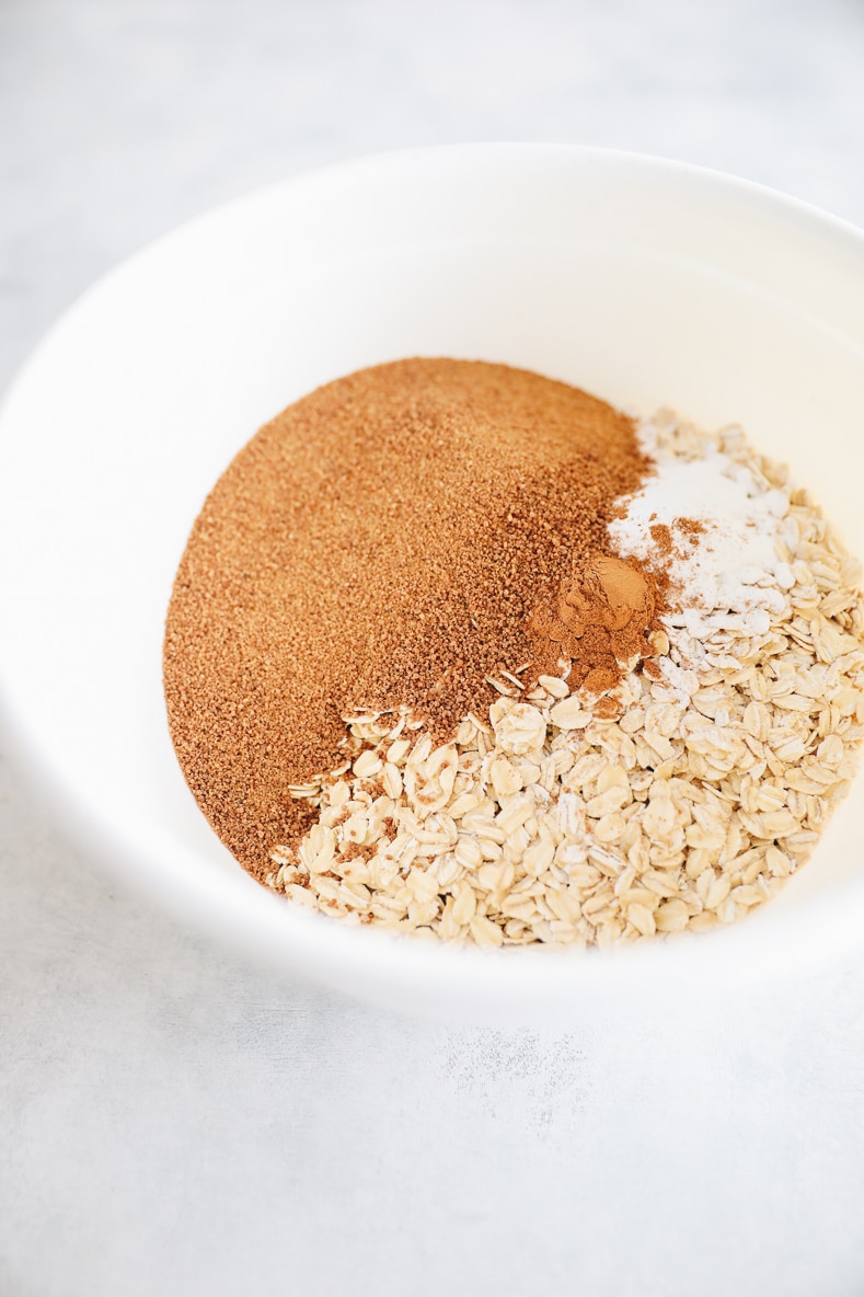 oats, flour, coconut sugar and cinnamon in a large white bowl.
