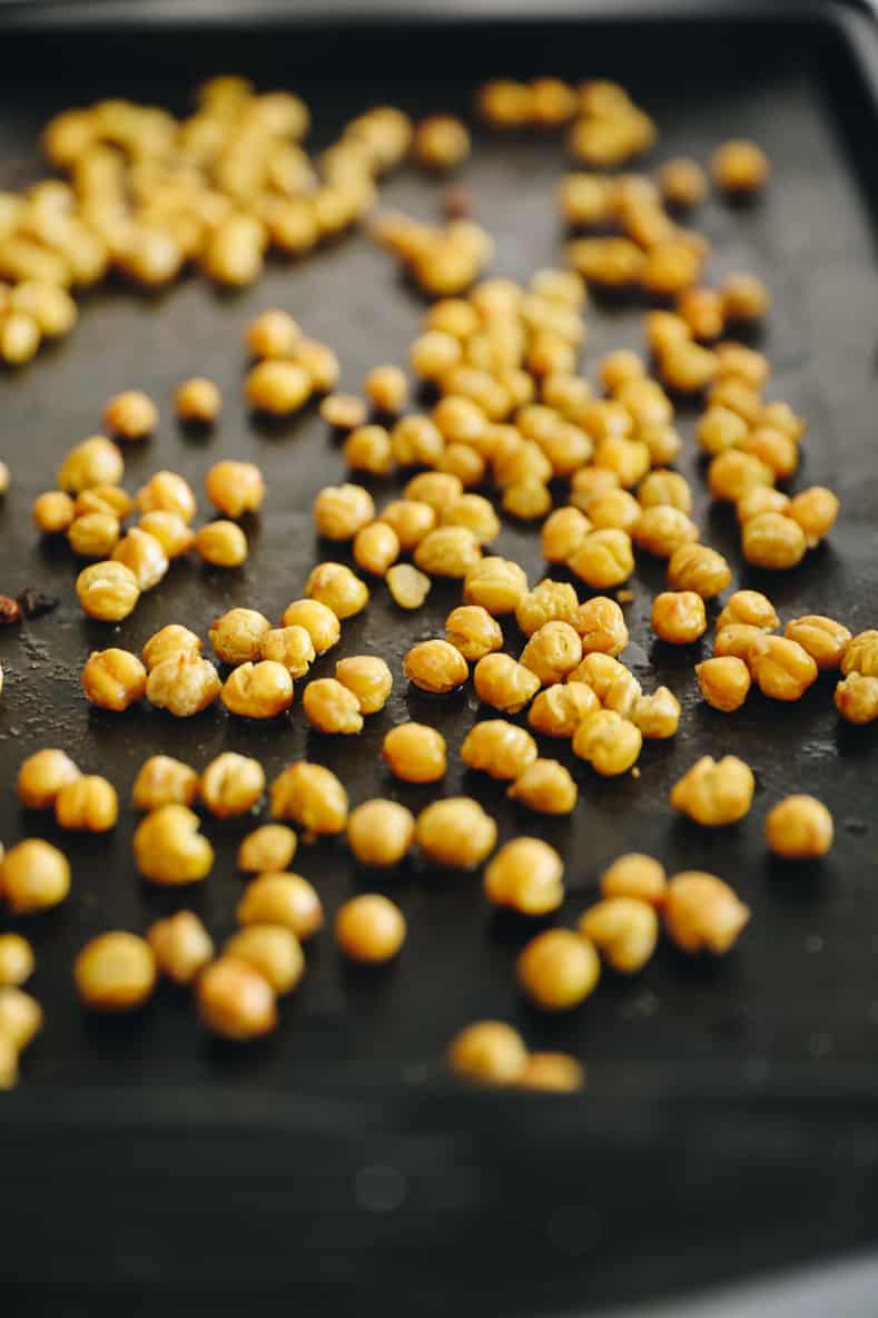 Roasted chickpeas scattered on a baking sheet.