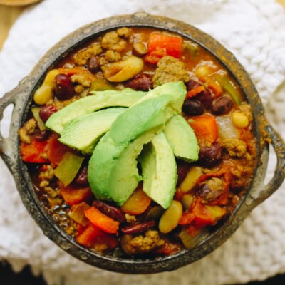 Overhead close up of beef chili in a bowl topped with sliced avocados.