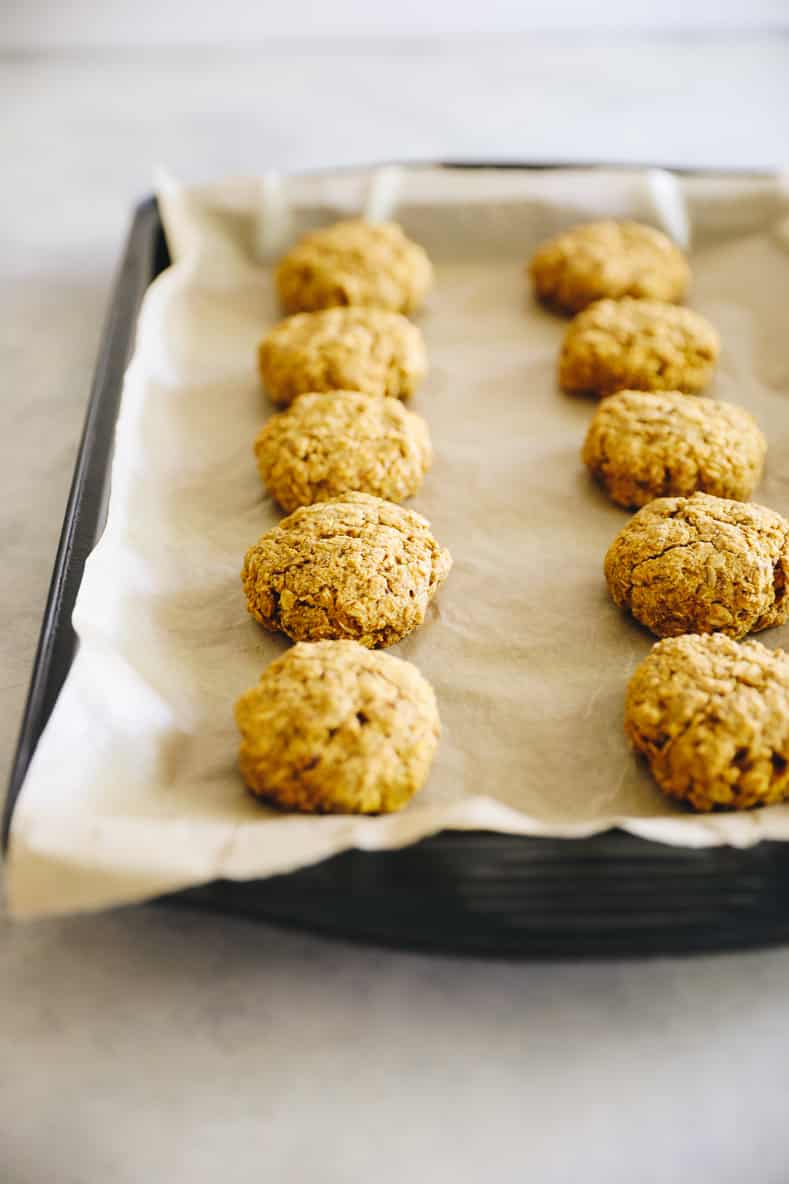 Sheet pan lined with parchment paper and topped with pumpkin breakfast cookies.
