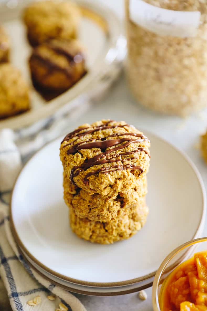 Angled shot of stacked pumpkin breakfast cookies drizzled with chocolate.