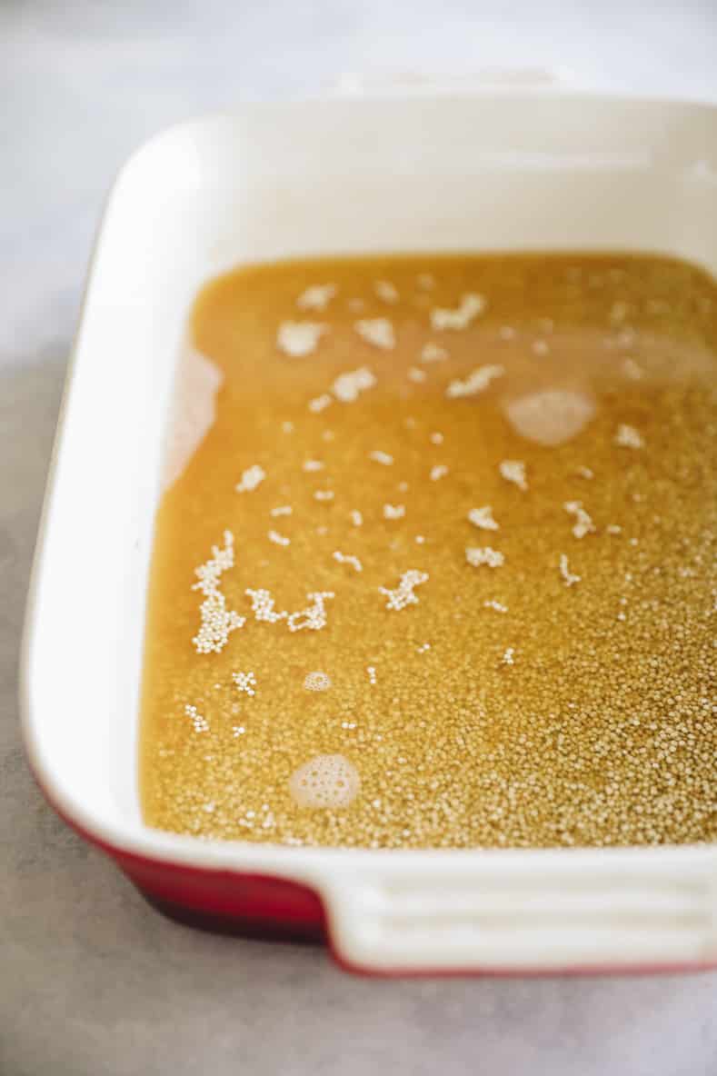 Quinoa and liquid in a baking dish prior to baking.