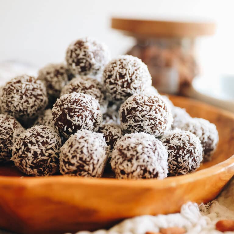 Close up shot of almond joy energy balls stacked on a wooden platter.