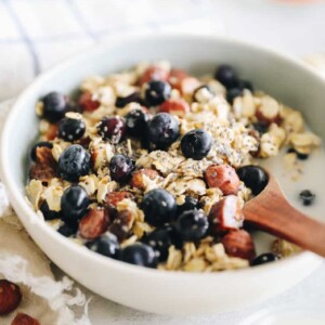 Bowl of bircher muesli topped with blueberries and milk.