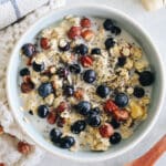 Bowl of bircher muesli topped with blueberries and milk.