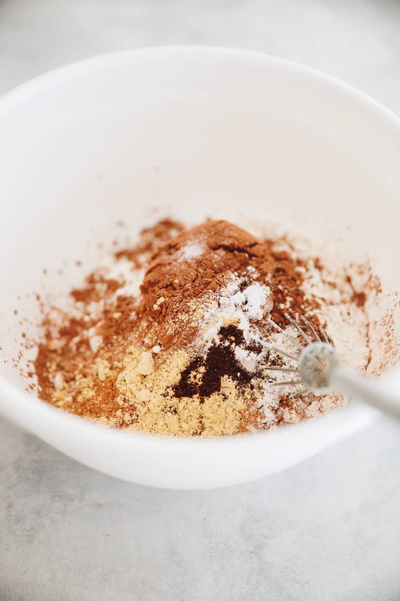 White mixing bowl with dry ingredients and whisk inside.