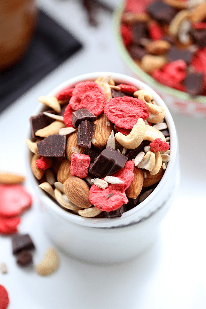 Bowl of trail mix made of mixed nuts, seeds, freeze dried strawberries and chocolate chunks.