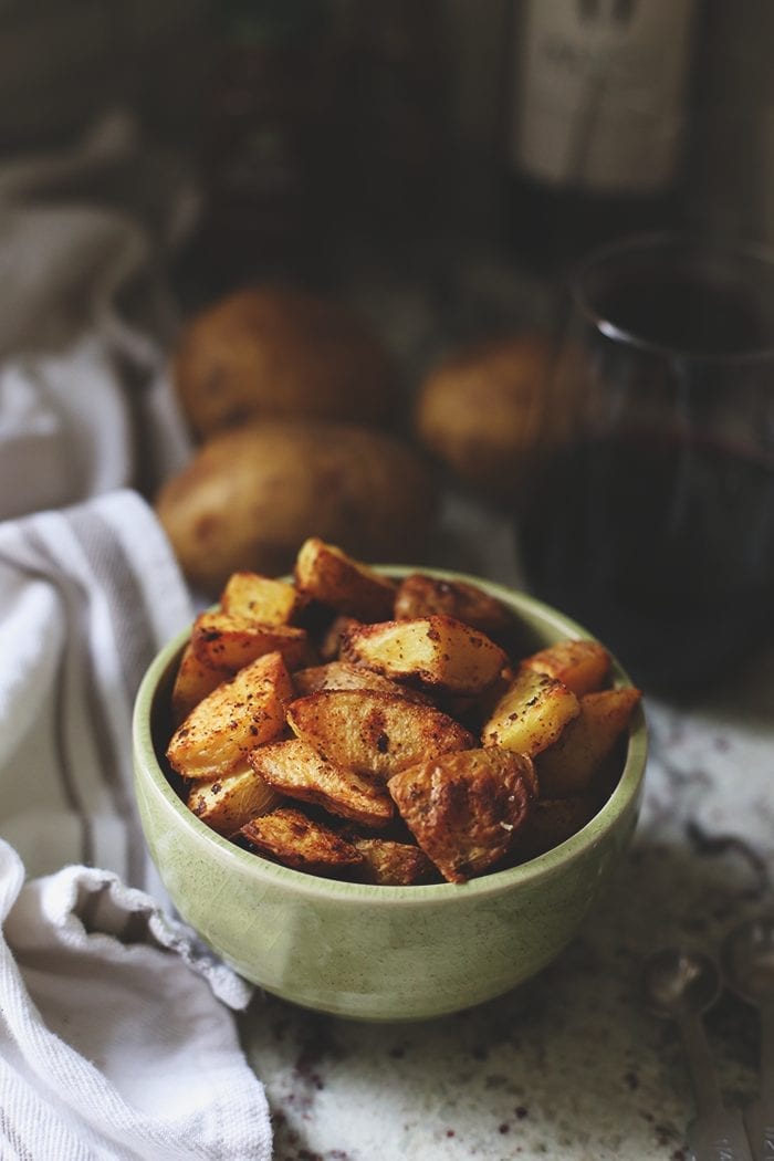 crispy roasted potatoes in a green bowl on the counter.