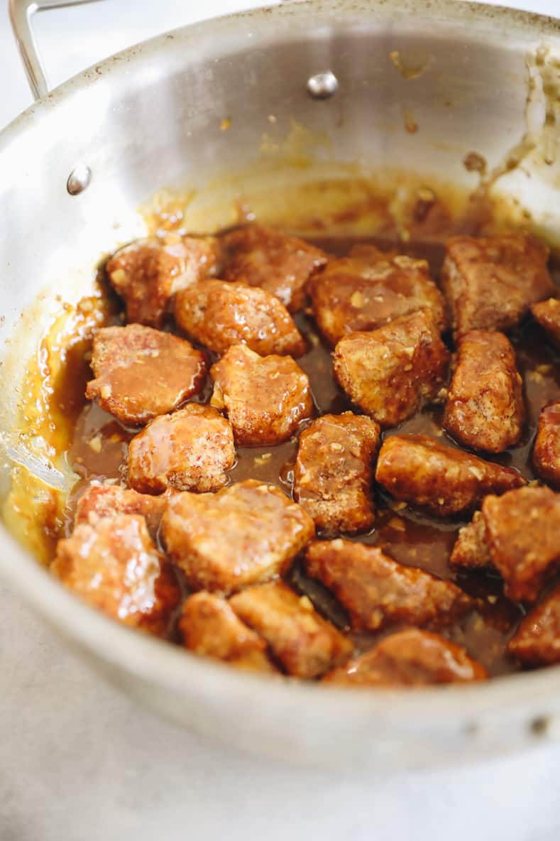 Sticky orange chicken cooking in saucepan.