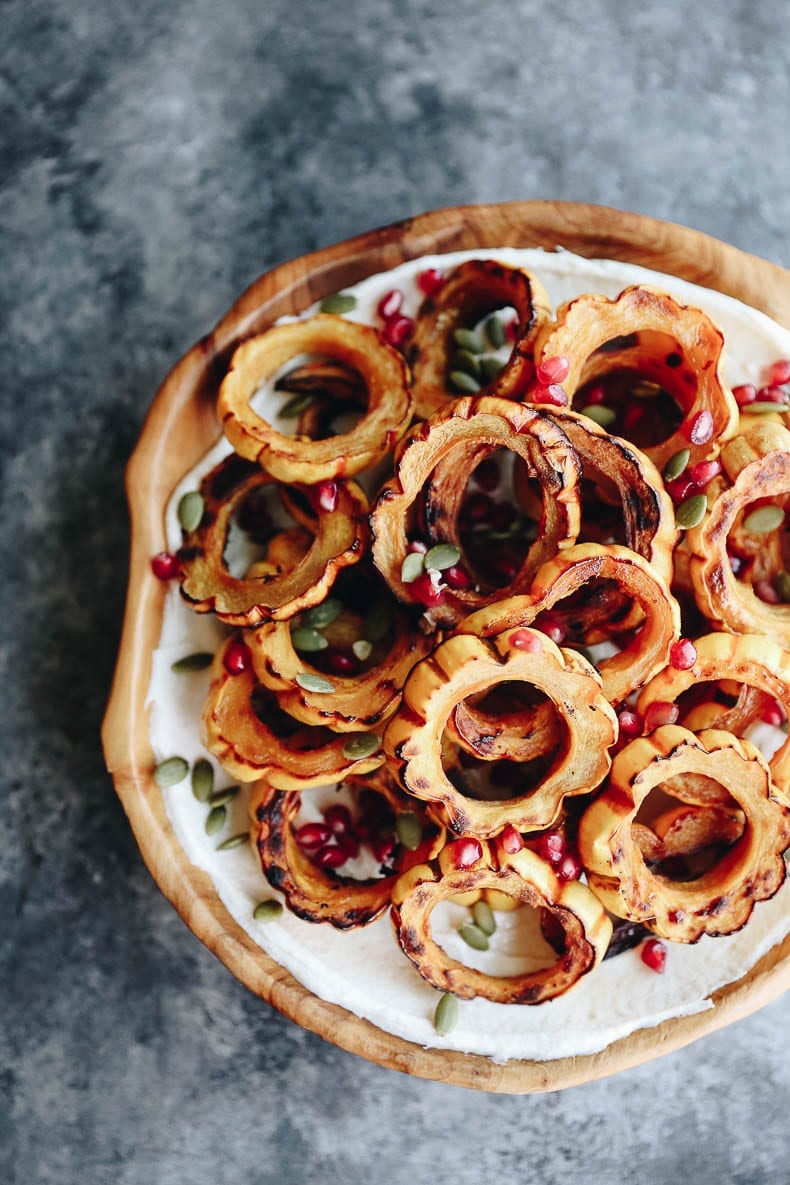 This Maple Roasted Squash with Tahini Yogurt Dressing makes a perfect weeknight dinner or Thanksgiving side dish. The squash caramelizes and is topped my a thick and creamy tahini yogurt dressing topped with pepitas and pomegranate seeds. You'll be going back for seconds! #thanksgiving #thanksgivingsides #glutenfree