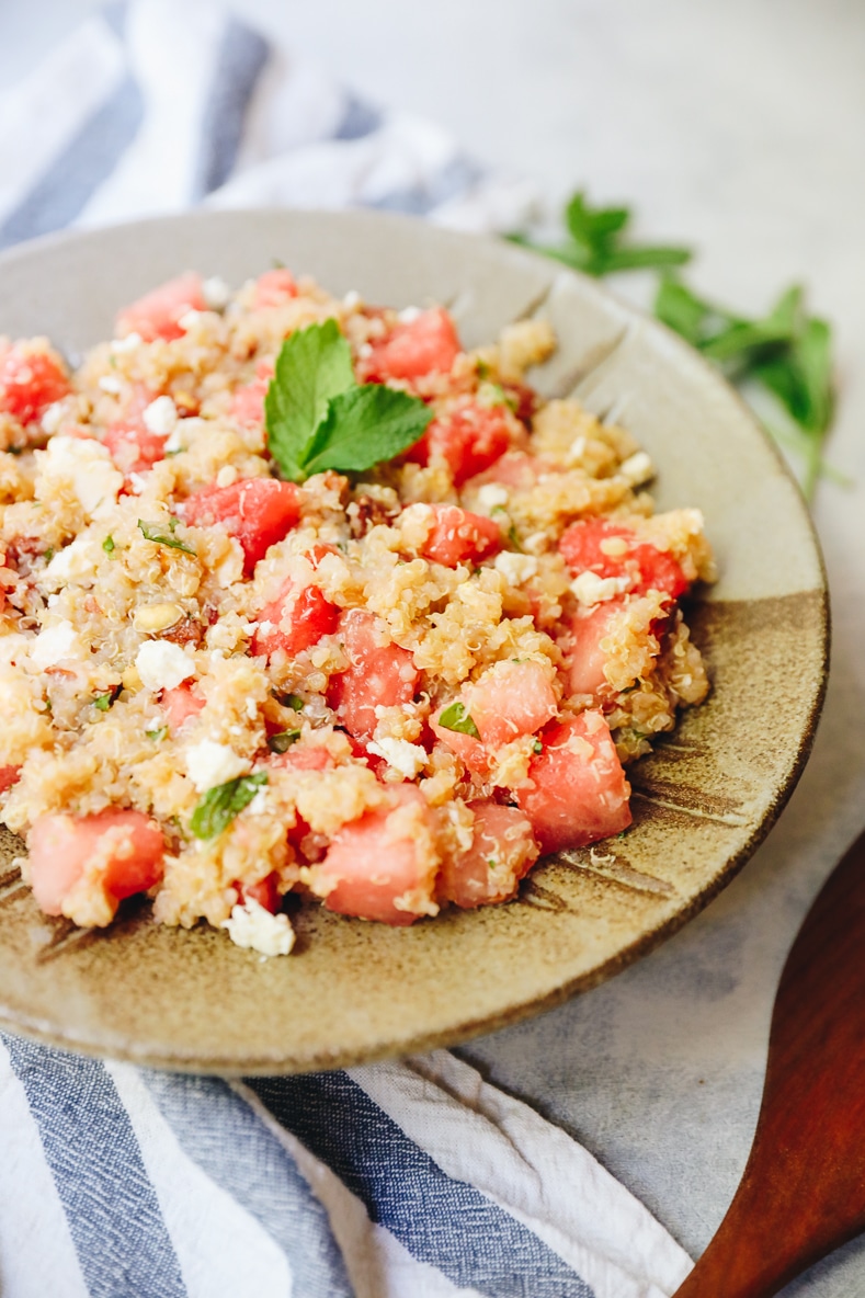 close-up of quinoa salad in a brown bowl with watermelon feta and mint