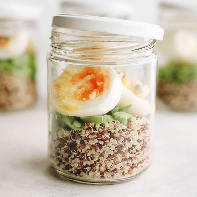 Small jar with quinoa, greens and eggs layered. 