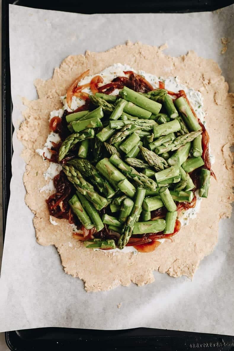 How to make a savory galette - step-by-step: step 3: roll out cold dough and top with goat cheese, asparagus + caramelized onions