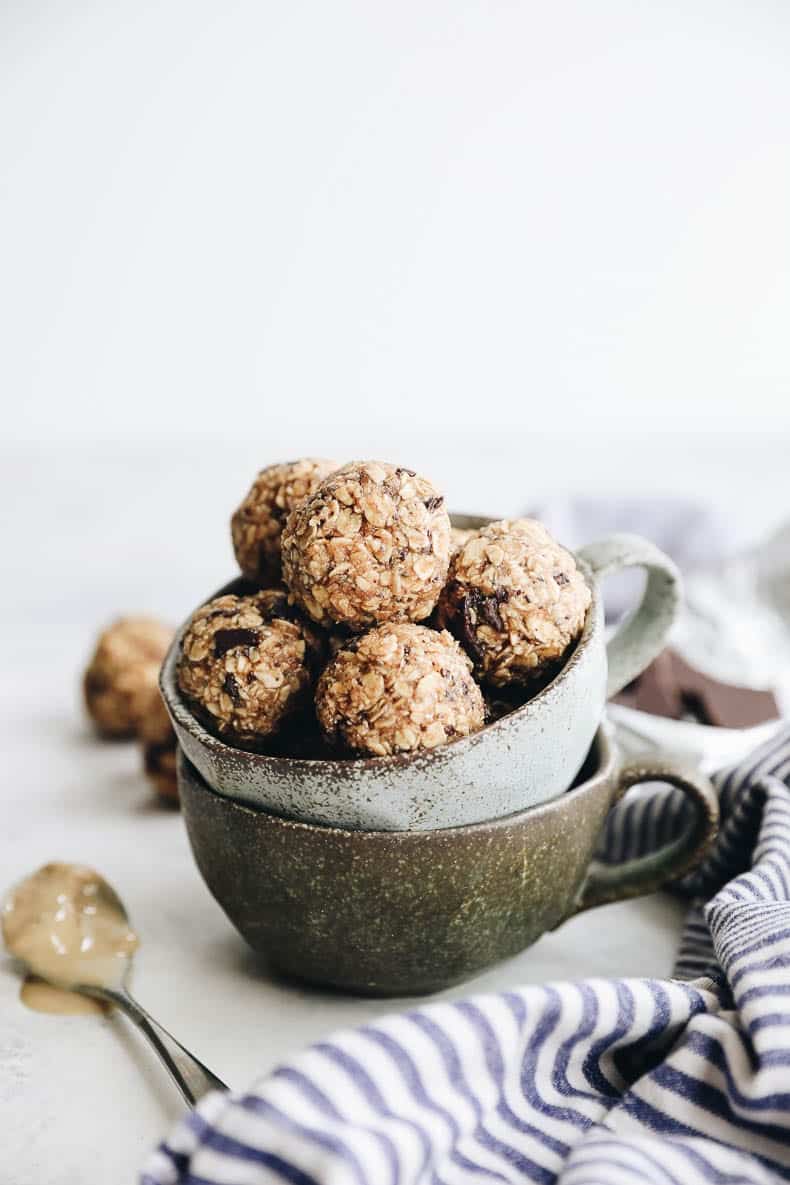 Two ceramic mugs stacked on top of each other and filled with tahini chocolate energy balls.