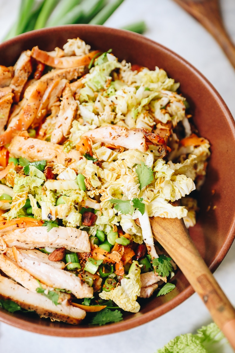 chinese chicken salad in a large brown bowl with a serving spoon.