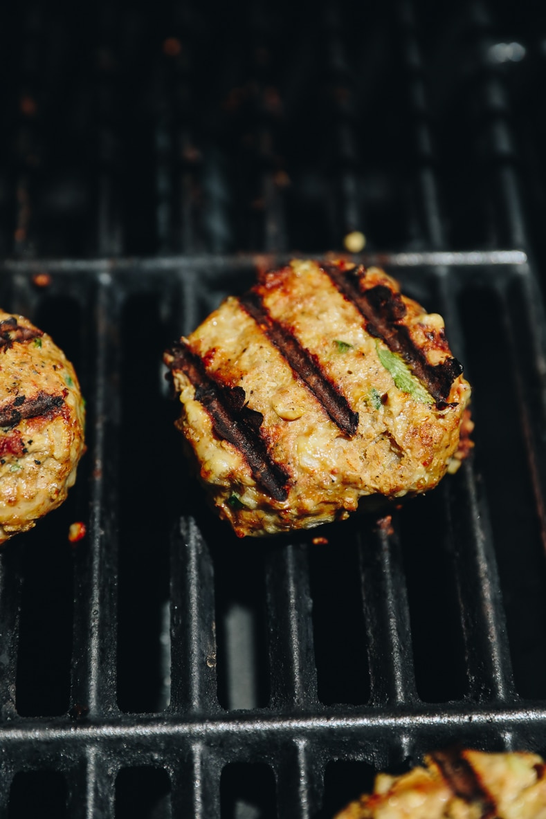 turkey burgers cooking on a grill.