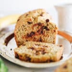 Zucchini banana bread loaf on a silver platter. Slice of bread cut away from the loaf.