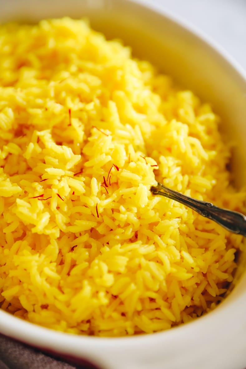 up-close saffron rice recipe in a baking dish with strands of saffron on top.