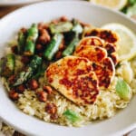 Close up shot of lemon orzo with asparagus and halloumi served on a white plate.