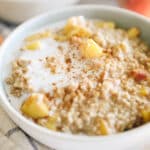 Oatmeal with peaches and cinnamon in a white bowl.