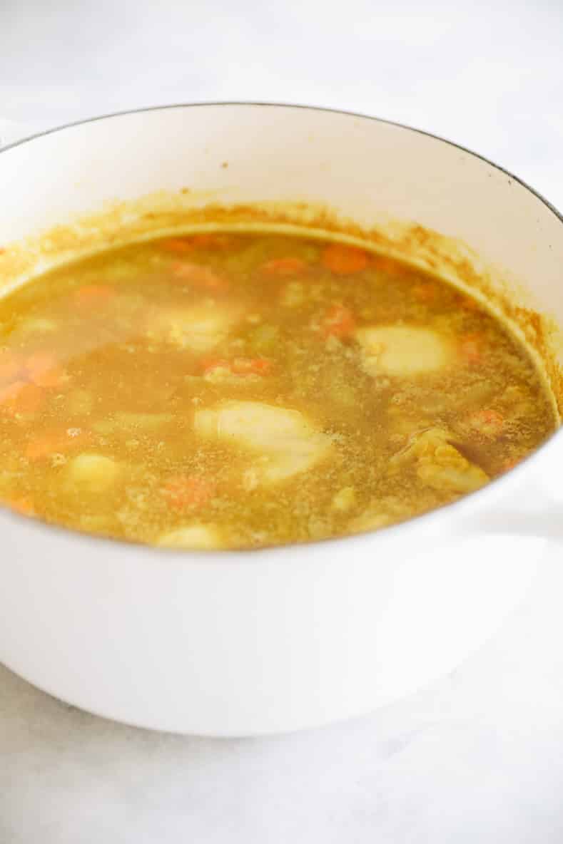 Chicken lentil soup in a white pot.