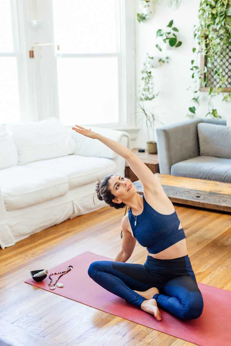 yoga teacher Davida Lederle sitting on her yoga mat with her yoga mat cleaner