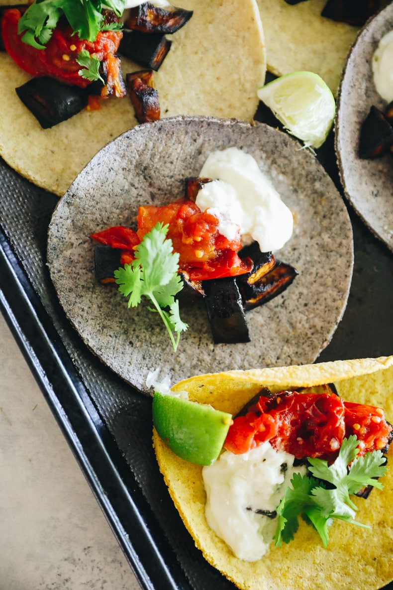 close up of eggplant tacos with tomatoes and burrata on a baking sheet