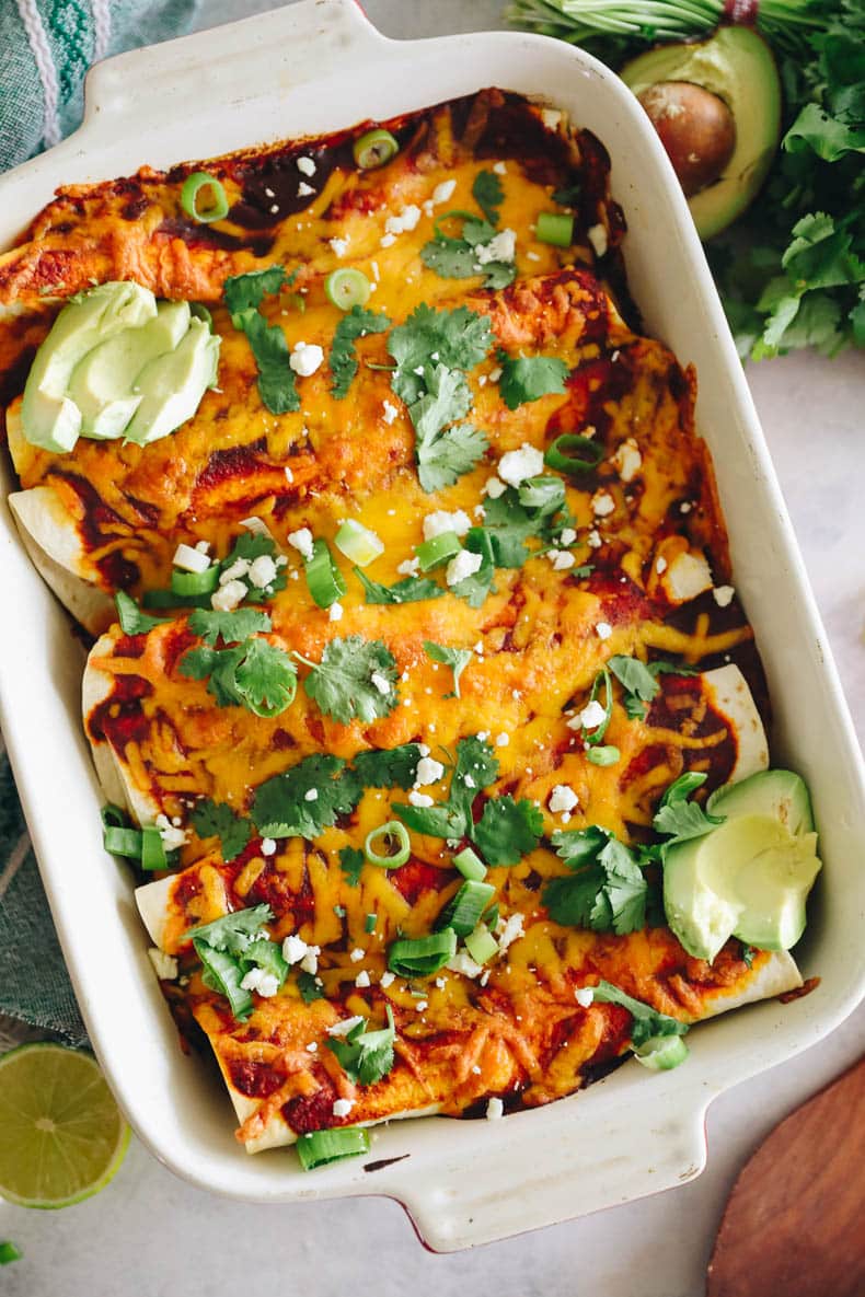 overhead photo of black bean enchiladas in a red baking dish.