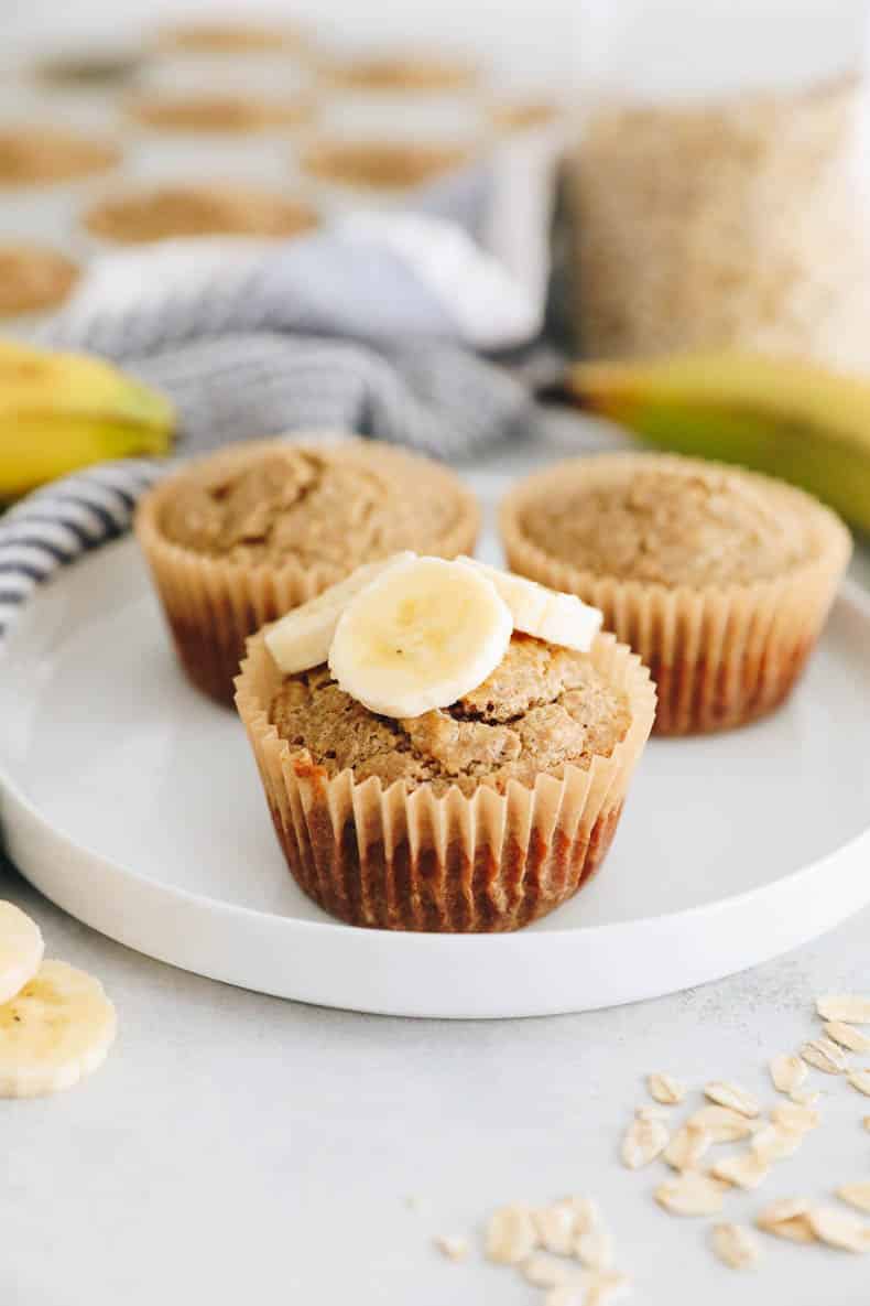 banana banana muffins on a white plate with sliced banana.