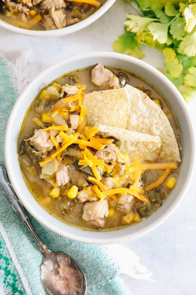 overhead image of green chili with pork, cheese and tortilla chips.
