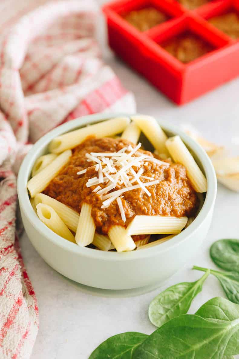 Hidden veggie pasta sauce over penne noodles in a green kids bowl.