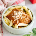 hidden veggie pasta sauce on penne pasta in a green kids bowl topped with parmesan cheese.