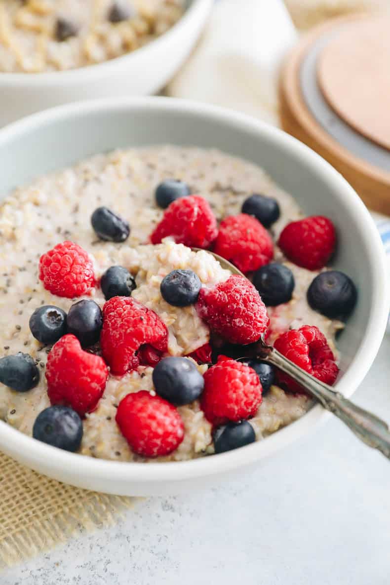 steel cut overnight oats in a bowl topped with raspberries, blueberries and chia sseds.