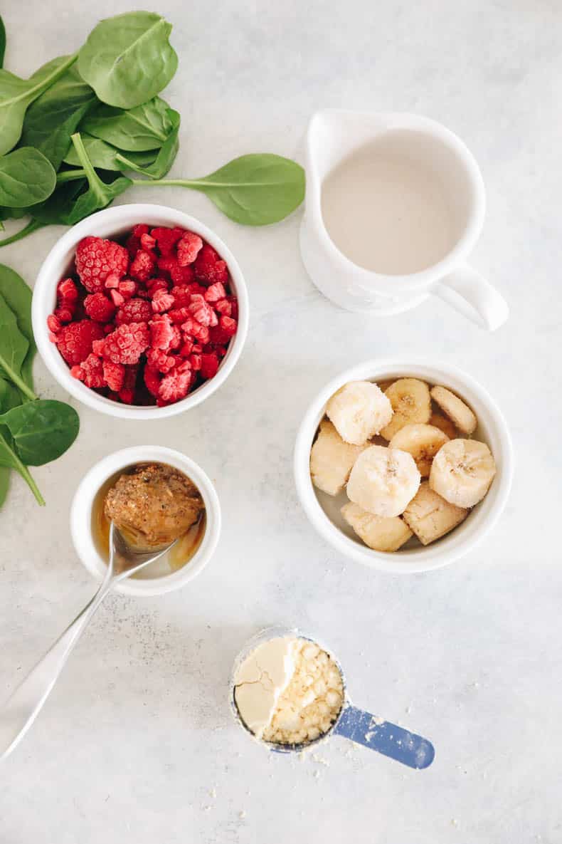 ingredients in a smoothie bowl recipe - frozen berries, frozen bananas, almond milk, nut butter, spinach and protein powder