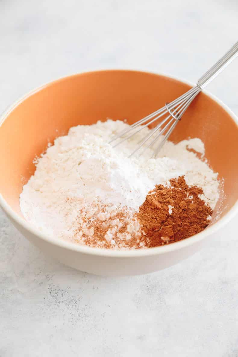 flour, cinnamon, baking powder and nutmeg in a mixing bowl with a whisk.