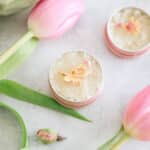 DIY lip scrub in a small pink metal can with pink tulips.