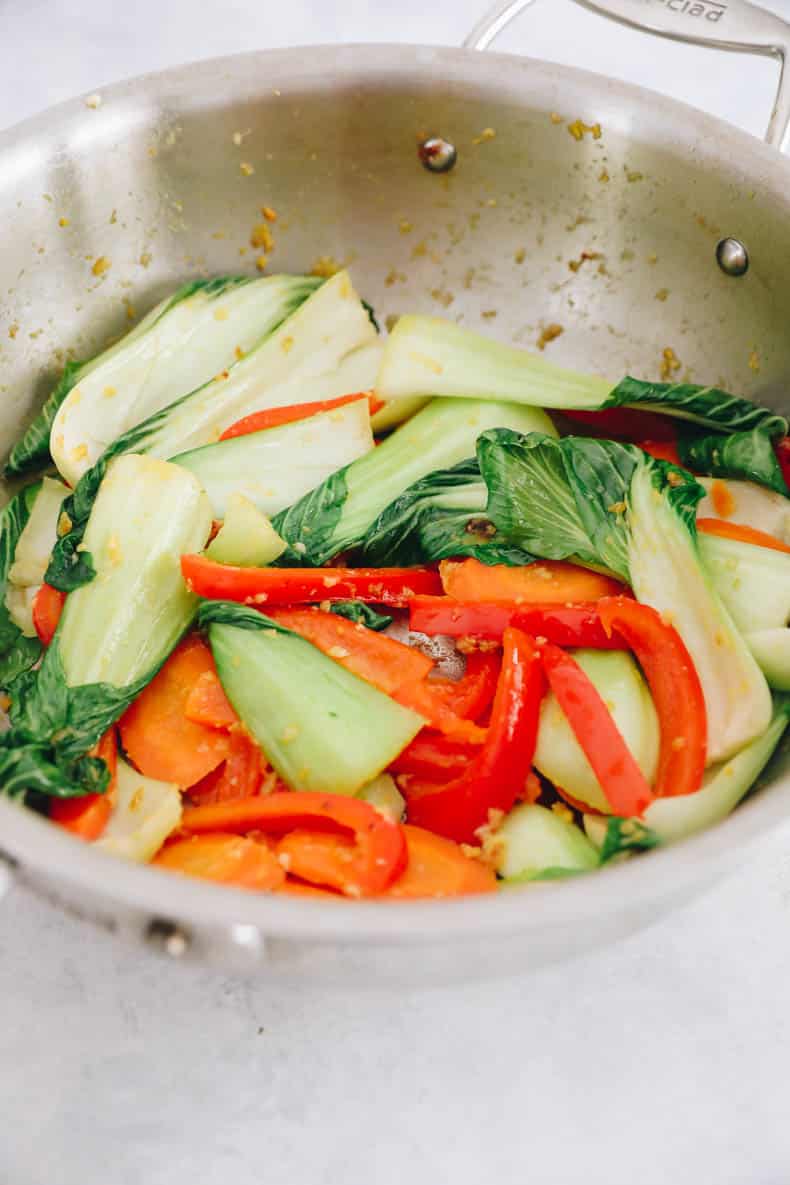 Carrots, red bell pepper, bok choy, garlic and ginger cooked in a wok.