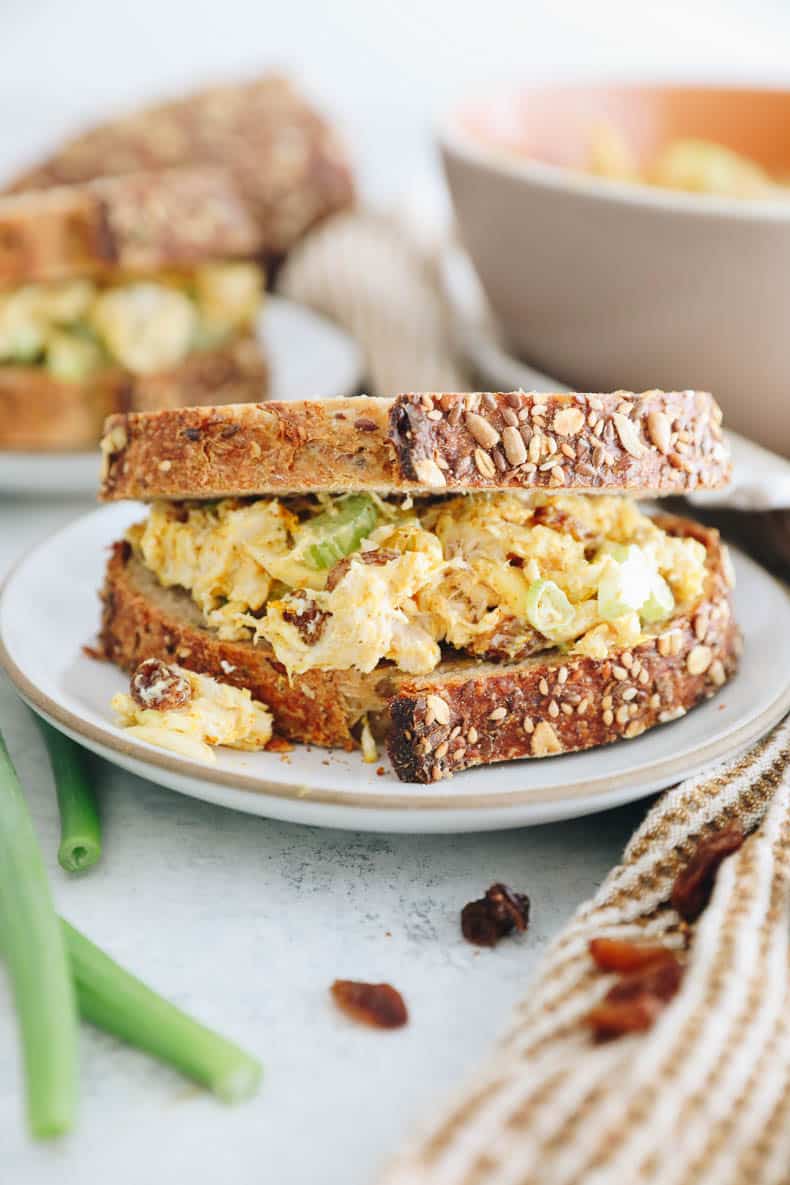 curry chicken salad in a sandwich on a white plate.