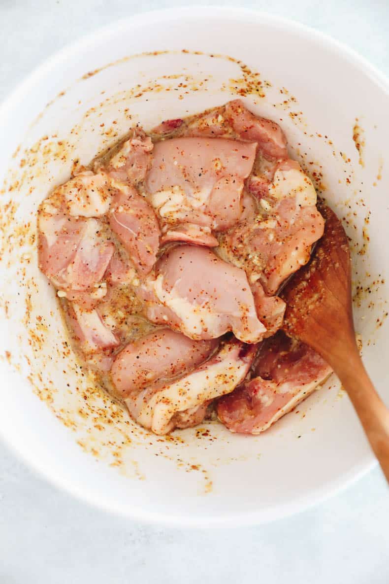 Honey mustard chicken marinating in a large bowl.