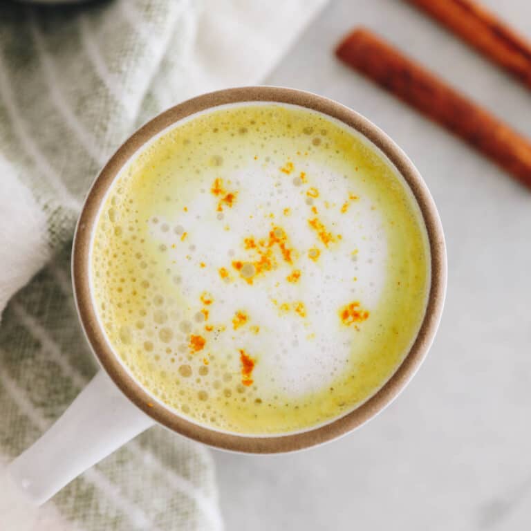 overhead image of a turmeric latte in a white and brown mug.