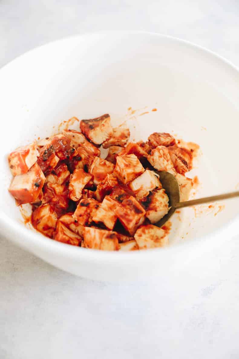 BBQ chicken coated in BBQ sauce in a white bowl.