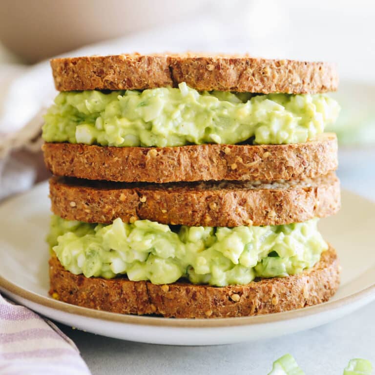 avocado egg salad on two sandwiches stacked on top of one another.