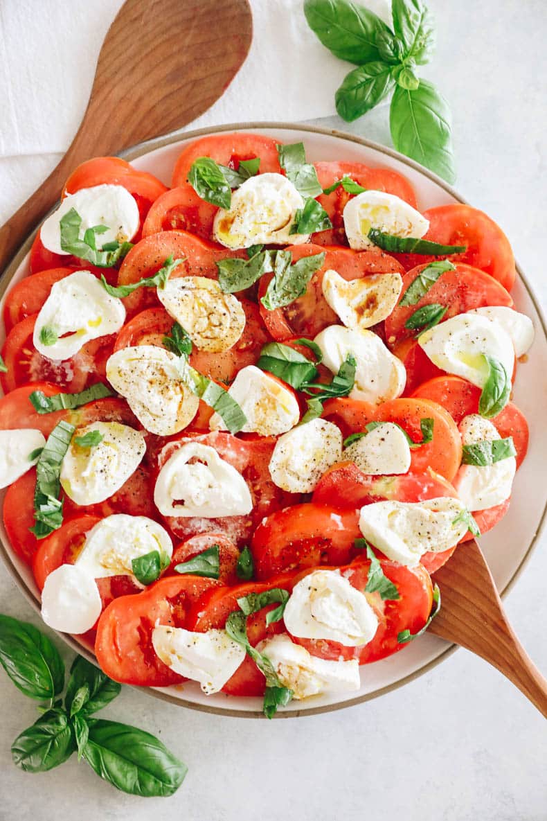 tomato burrata salad on a large platter drizzled with olive oil and balsamic.