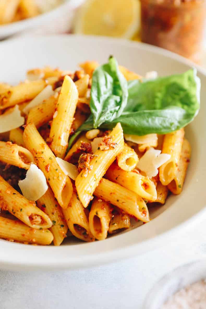 sun dried tomato pesto on penne pasta in white bowl.